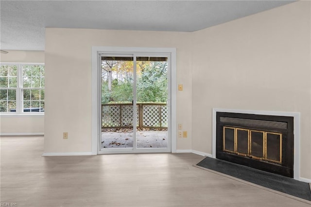 unfurnished living room with a textured ceiling and light hardwood / wood-style flooring