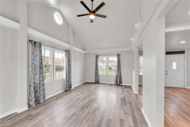 empty room with high vaulted ceiling, light hardwood / wood-style flooring, and ceiling fan