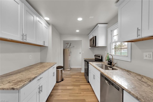 kitchen with white cabinets, sink, stainless steel appliances, and light hardwood / wood-style flooring