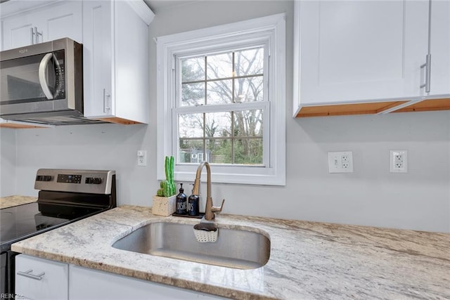 kitchen featuring white cabinetry, sink, light stone countertops, and appliances with stainless steel finishes