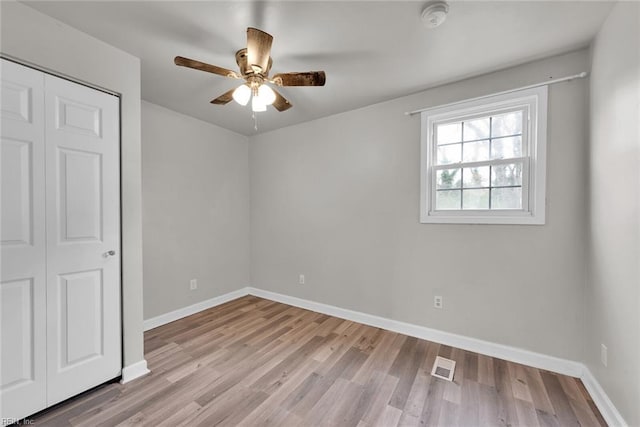 unfurnished bedroom with ceiling fan, light wood-type flooring, and a closet