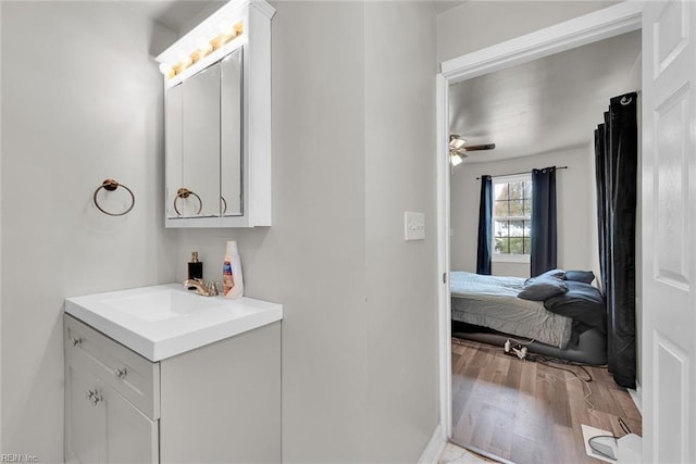 bathroom with hardwood / wood-style floors, ceiling fan, and vanity