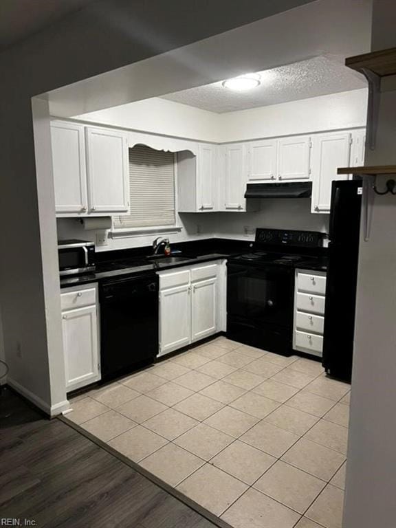 kitchen featuring black appliances, white cabinetry, sink, and light tile patterned floors