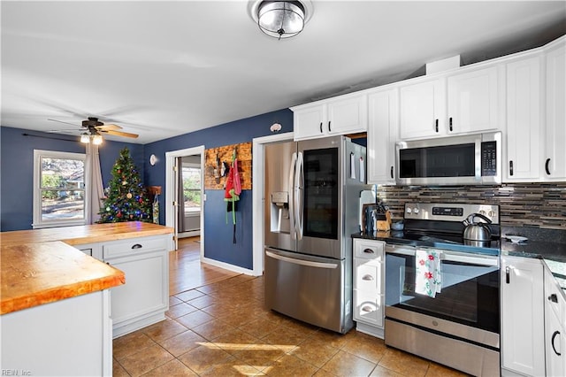 kitchen featuring white cabinets, stainless steel appliances, wood counters, and a healthy amount of sunlight