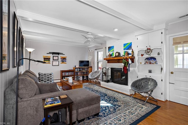 living room featuring ceiling fan, beamed ceiling, a healthy amount of sunlight, and wood-type flooring