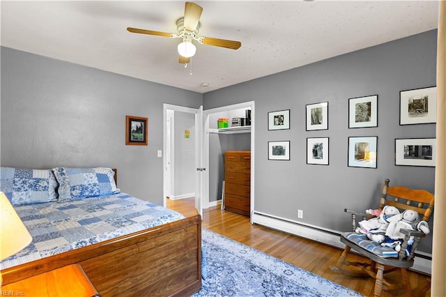 bedroom featuring ceiling fan, baseboard heating, and light hardwood / wood-style flooring