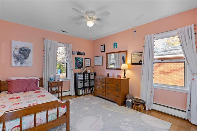 bedroom featuring ceiling fan, light hardwood / wood-style floors, and a baseboard radiator