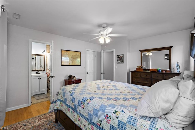 bedroom featuring ensuite bath, ceiling fan, sink, and light wood-type flooring