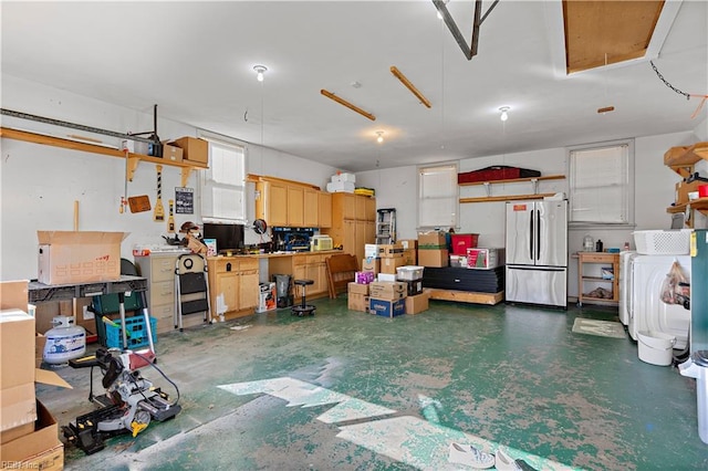 garage with stainless steel fridge, a workshop area, and washer / clothes dryer