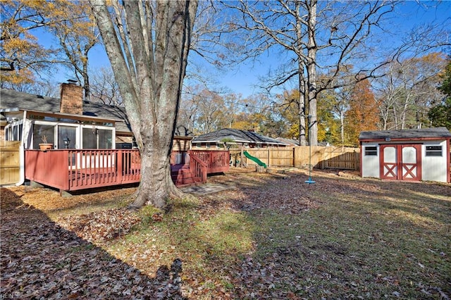 view of yard featuring a sunroom, a storage unit, and a wooden deck