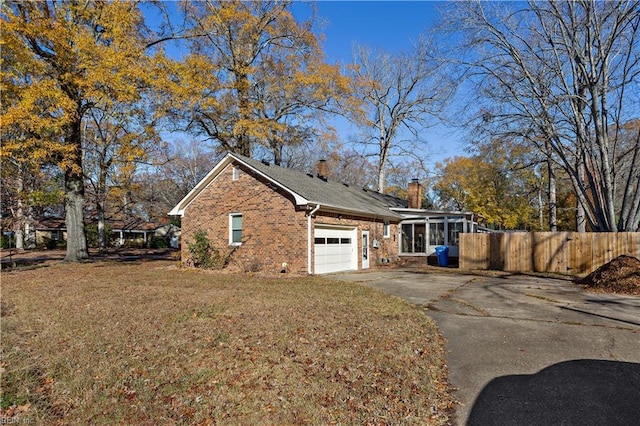 view of home's exterior featuring a yard, a garage, and a sunroom