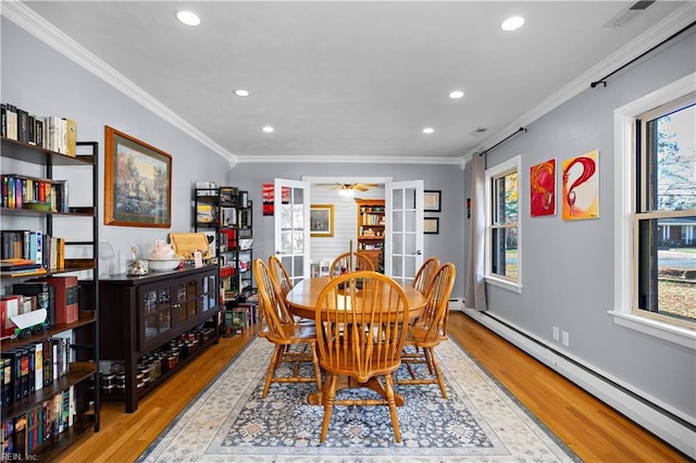 dining area with ornamental molding, light hardwood / wood-style floors, and a baseboard heating unit