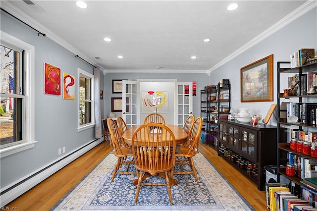 dining area featuring light wood-type flooring, baseboard heating, and crown molding