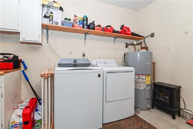 laundry room featuring washer and clothes dryer, cabinets, a wood stove, and water heater