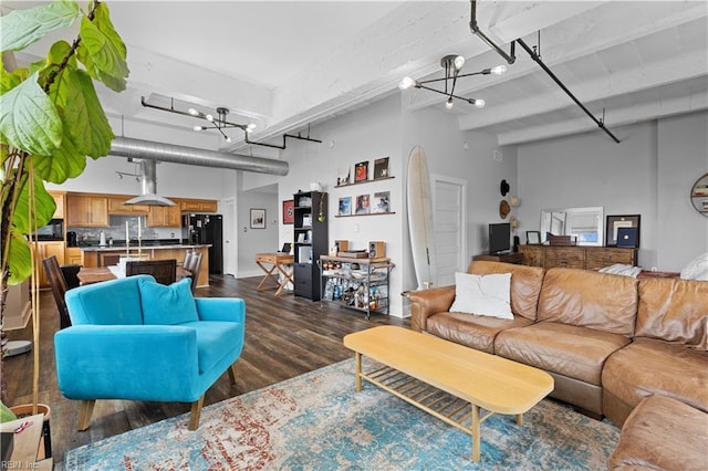 living room featuring beam ceiling, dark hardwood / wood-style flooring, a towering ceiling, and an inviting chandelier