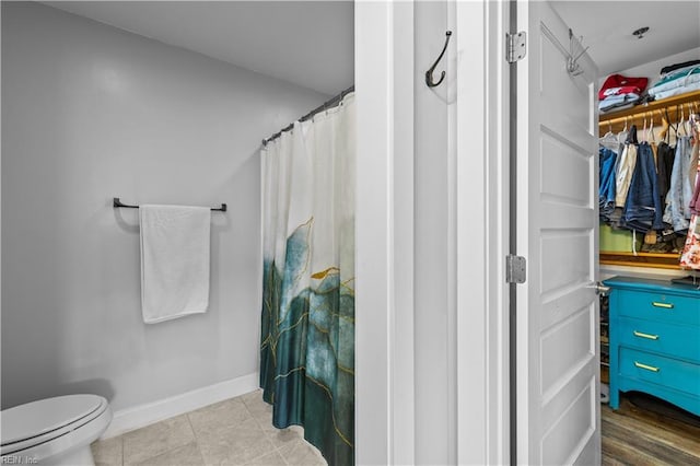 bathroom with toilet, a shower with curtain, and tile patterned floors