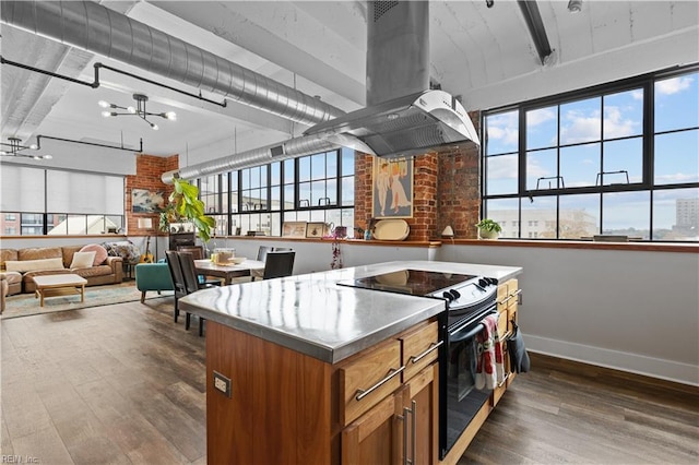 kitchen with dark hardwood / wood-style flooring, island range hood, black electric range oven, and brick wall