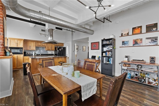 dining area featuring beamed ceiling, dark hardwood / wood-style floors, a towering ceiling, and a chandelier