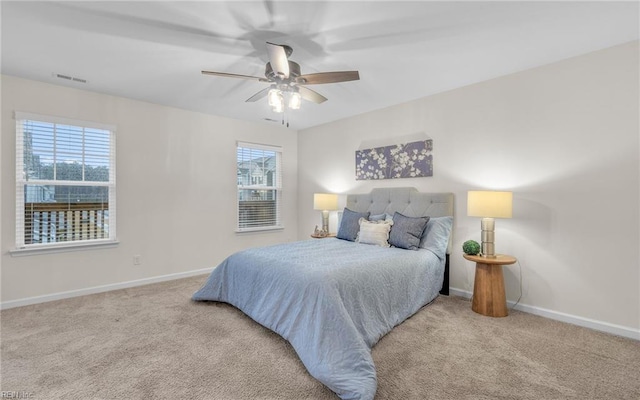 bedroom with light carpet, multiple windows, and ceiling fan