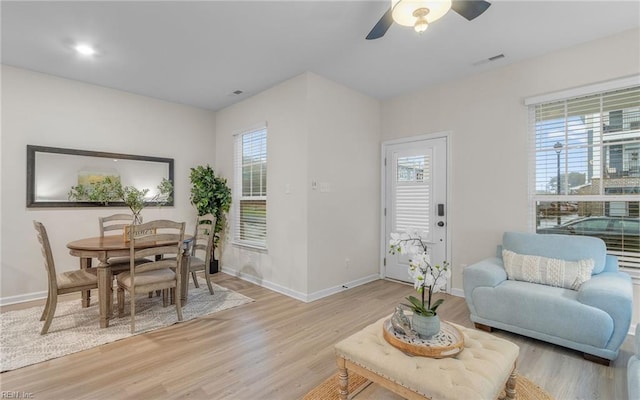 living room featuring plenty of natural light, ceiling fan, and light wood-type flooring