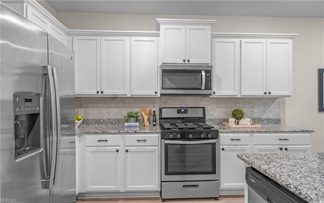 kitchen with light hardwood / wood-style flooring, light stone countertops, appliances with stainless steel finishes, tasteful backsplash, and white cabinetry