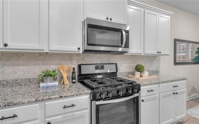 kitchen featuring white cabinets, light stone countertops, light wood-type flooring, and stainless steel appliances