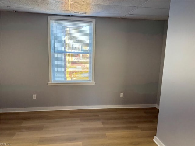 empty room with a paneled ceiling and wood-type flooring