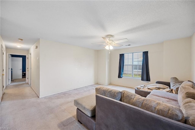 living room with light carpet, ceiling fan, and a textured ceiling