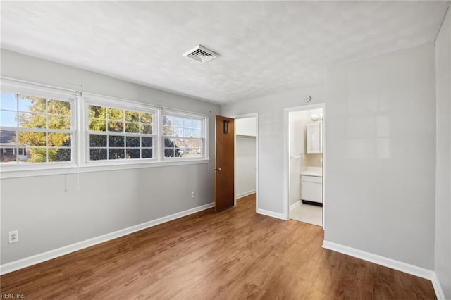 unfurnished bedroom with light wood-type flooring and ensuite bathroom