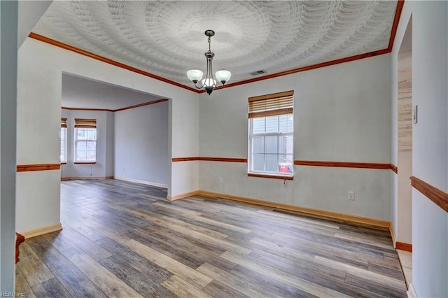 empty room with ornamental molding, a healthy amount of sunlight, and hardwood / wood-style flooring