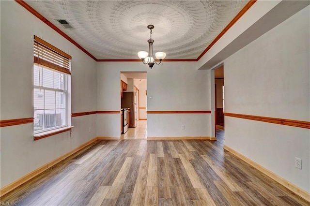 unfurnished room featuring crown molding, hardwood / wood-style floors, and a chandelier