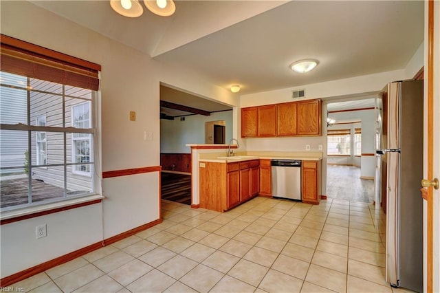 kitchen featuring light tile patterned floors, kitchen peninsula, sink, and appliances with stainless steel finishes