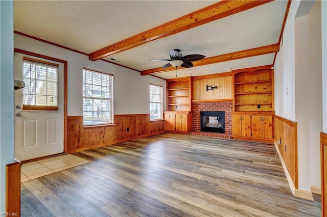 unfurnished living room with a brick fireplace, a wealth of natural light, a textured ceiling, and hardwood / wood-style flooring