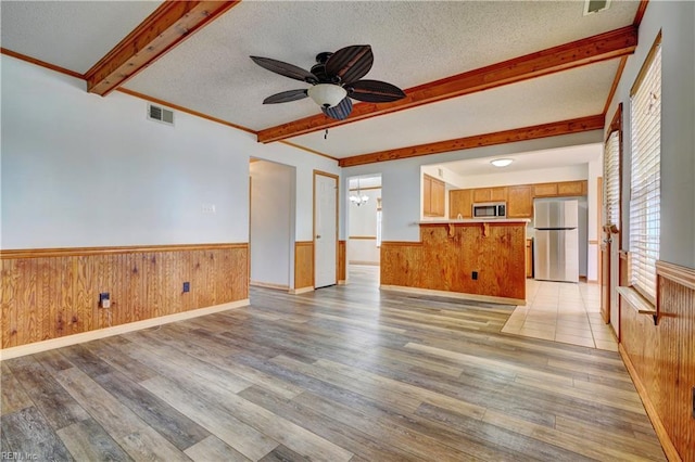 unfurnished living room featuring ceiling fan with notable chandelier, a textured ceiling, and light hardwood / wood-style flooring