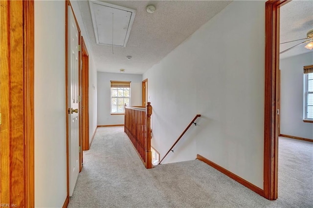 corridor with light colored carpet and a textured ceiling