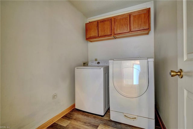 laundry room with cabinets, washing machine and clothes dryer, and light hardwood / wood-style flooring