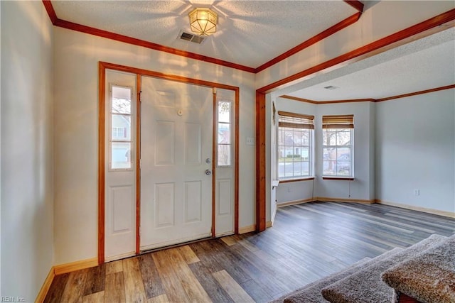 entrance foyer with a healthy amount of sunlight, crown molding, wood-type flooring, and a textured ceiling