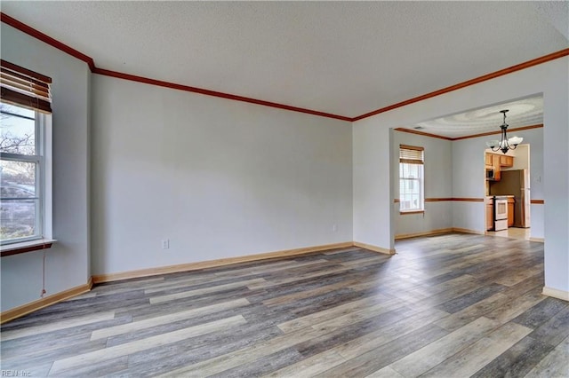 unfurnished room featuring hardwood / wood-style floors, an inviting chandelier, plenty of natural light, and ornamental molding