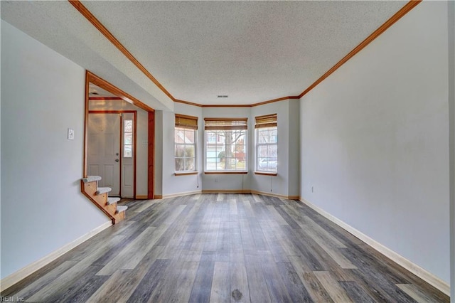 empty room with dark hardwood / wood-style floors, crown molding, and a textured ceiling