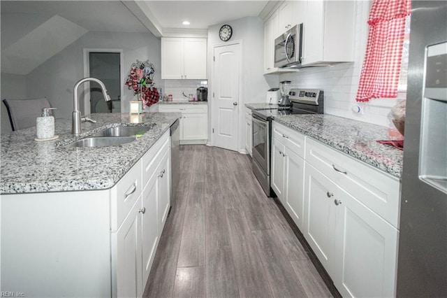 kitchen with stainless steel appliances, dark wood-type flooring, sink, white cabinetry, and an island with sink