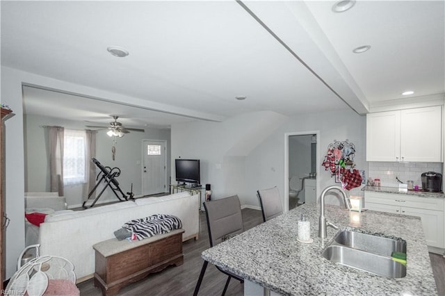 kitchen featuring beam ceiling, sink, tasteful backsplash, light stone counters, and white cabinets