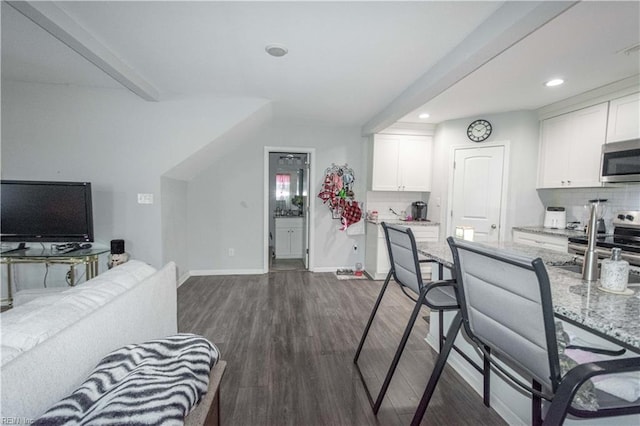 kitchen with white cabinets, light stone counters, stainless steel appliances, and dark wood-type flooring