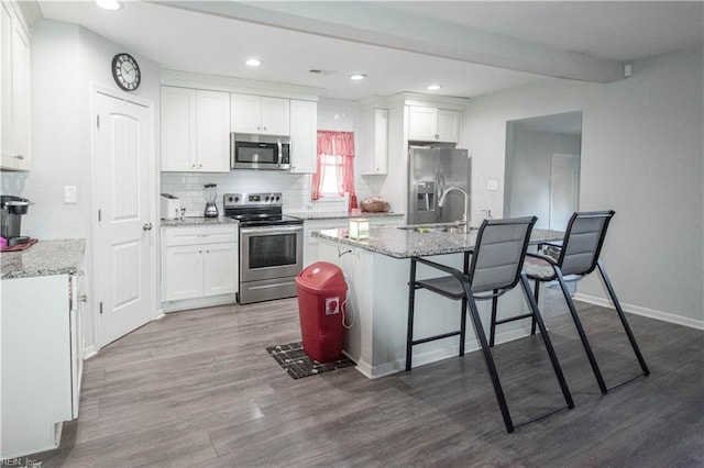 kitchen with white cabinetry, stainless steel appliances, and light stone counters