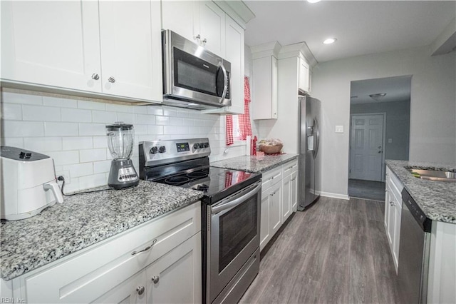 kitchen featuring light stone counters, white cabinetry, dark wood-type flooring, and appliances with stainless steel finishes