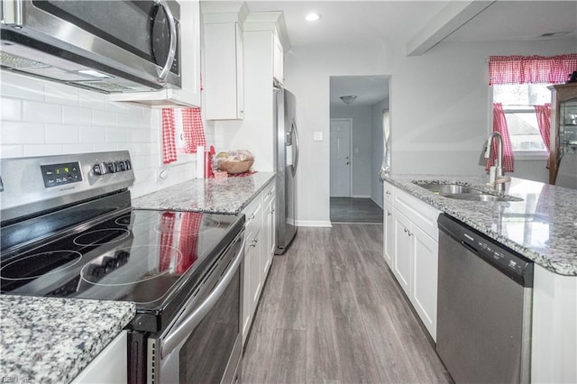 kitchen with light stone counters, sink, white cabinets, and stainless steel appliances