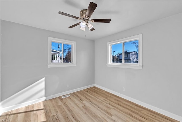 spare room featuring ceiling fan, a healthy amount of sunlight, and light wood-type flooring