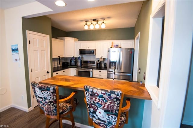 kitchen featuring white cabinets, decorative backsplash, dark hardwood / wood-style floors, appliances with stainless steel finishes, and butcher block countertops