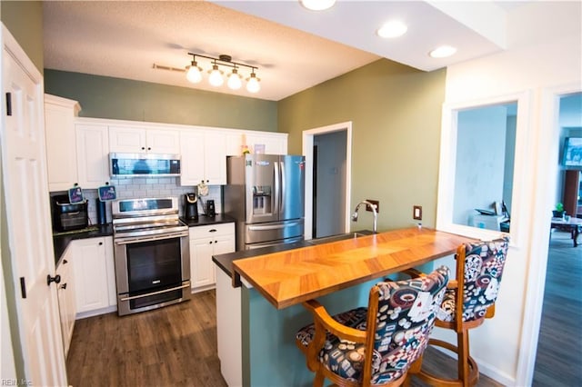 kitchen with stainless steel appliances, white cabinetry, dark hardwood / wood-style floors, and sink