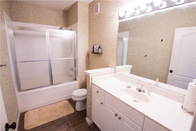 full bathroom with wood-type flooring, vanity, toilet, and bath / shower combo with glass door