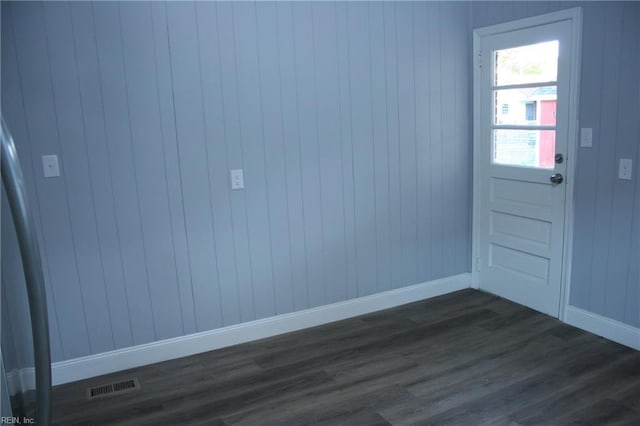 doorway to outside with wooden walls and dark hardwood / wood-style flooring